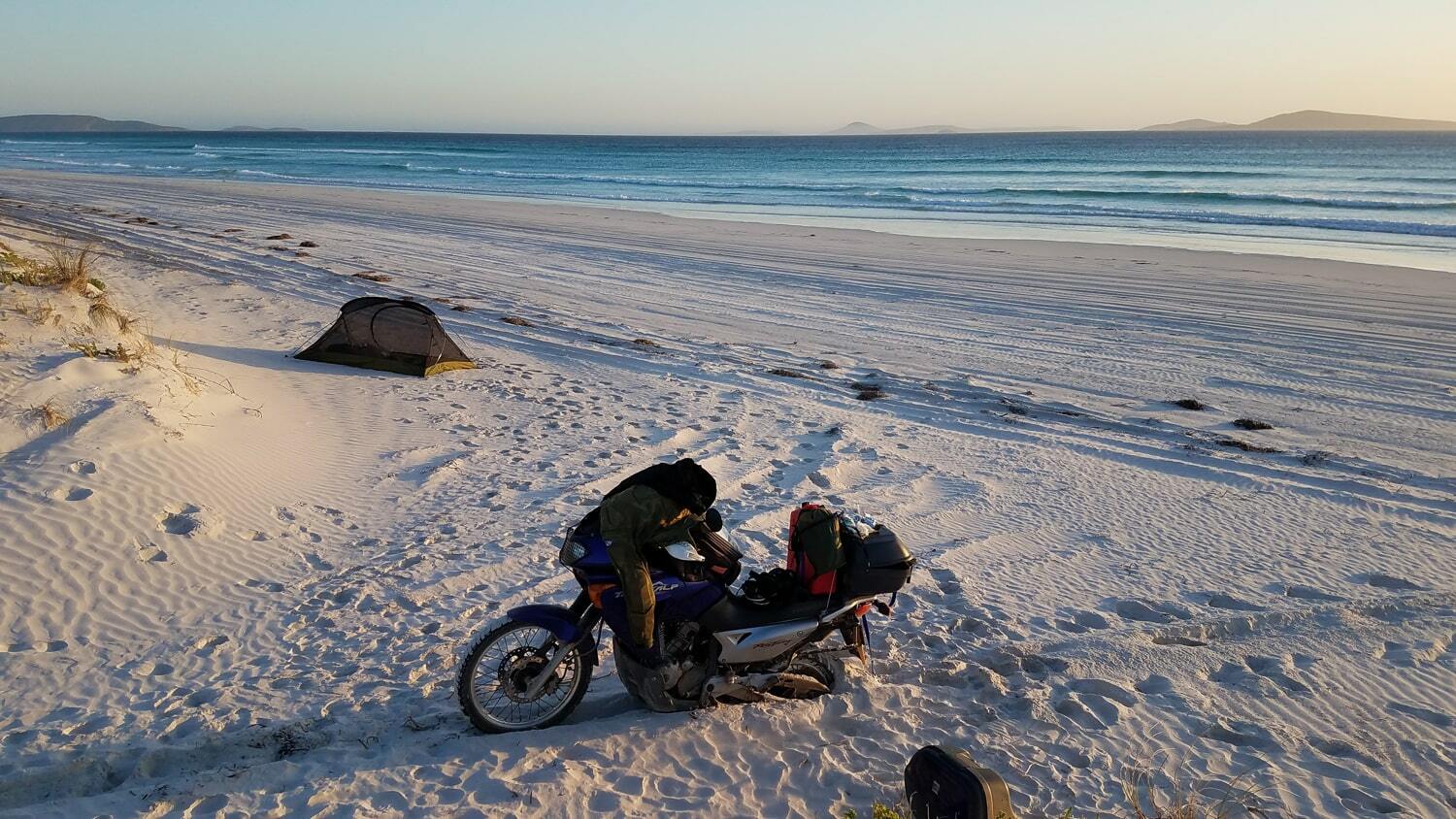 motorcycle with the rear wheel stuck in deep white sand on a beach