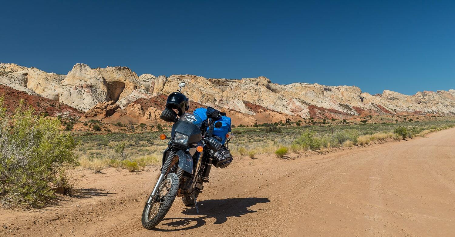 motorcycle parked on a dirt road and sandstone reef behind
