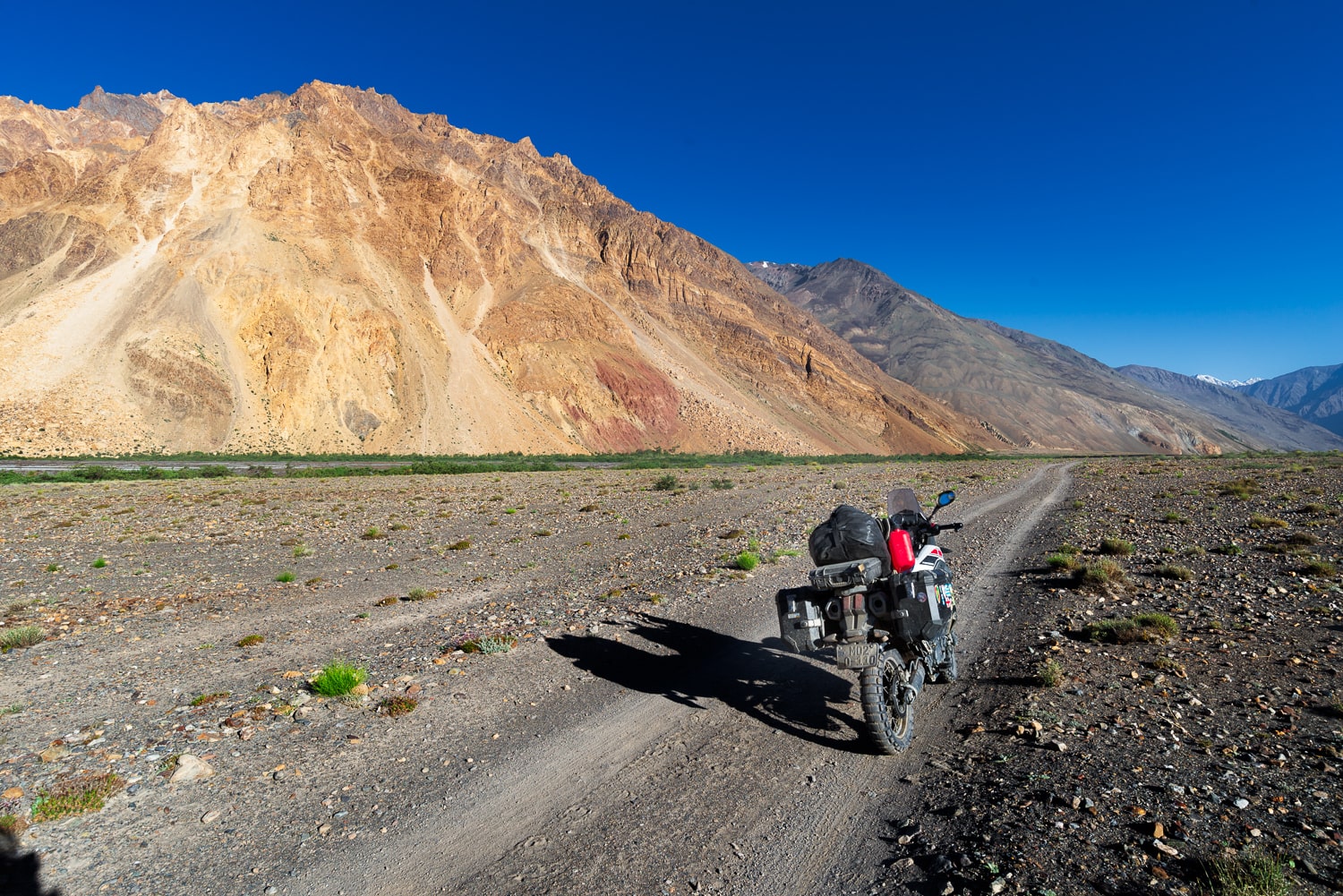 motorcycle parked in a dry valley surrounded by colorful mountains