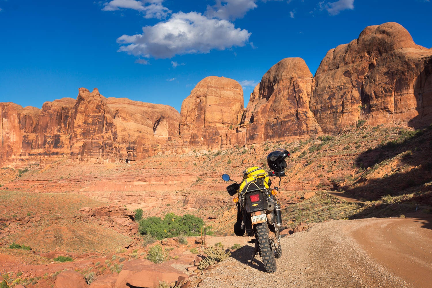 a motorcycle parked with red sandstone cliffs behind