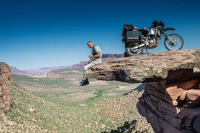 a rider and bike on an overhanging rock