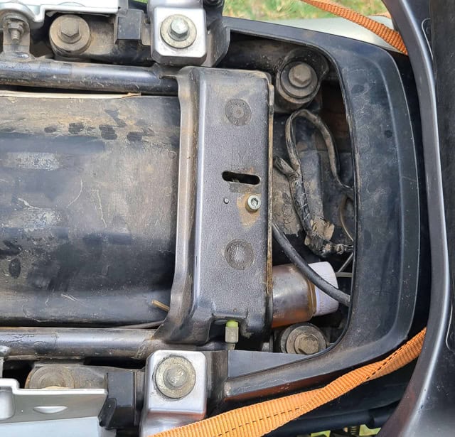 plastic bottle stuffed under a motorcycle seat housing