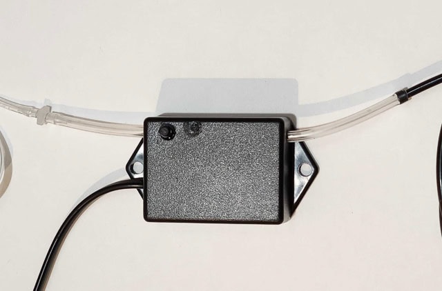 hoses on two sides of a black plastic box connected to other hoses