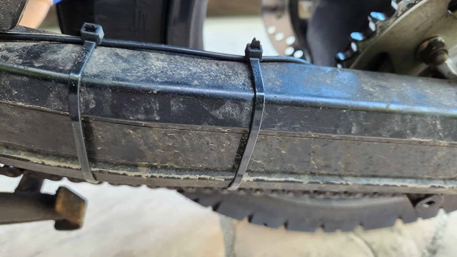 photo of a black hose routed along the top inner edge of the swingarm