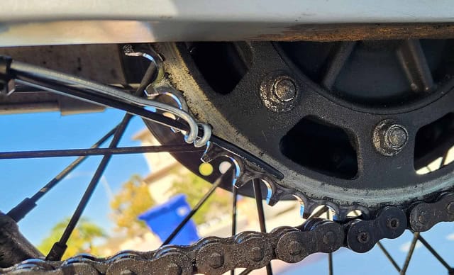 photo of a wire loop at the bottom of a swingarm holding hose in place